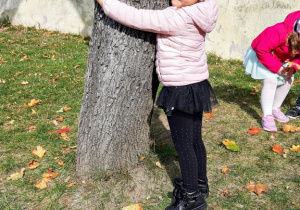 Zuzia przytula się do drzewa.